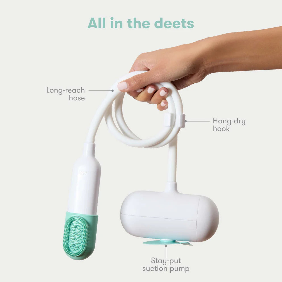 Hand holding a white and green cleaning device with labeled parts on a light background