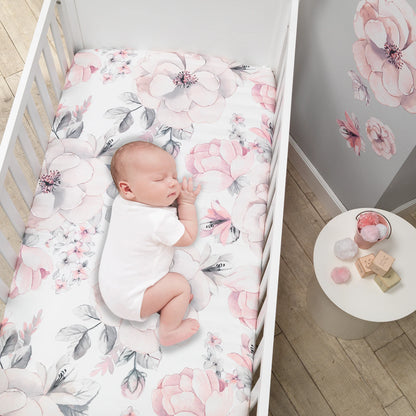 Newborn baby sleeping in a crib with floral bedding in a nursery setting.